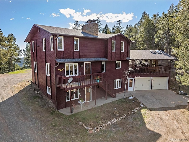 view of front of property with a garage, a wooden deck, and a patio