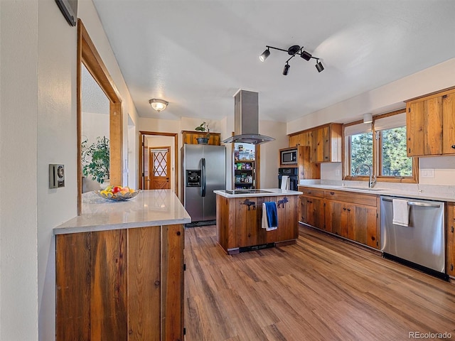 kitchen with island exhaust hood, stainless steel appliances, a center island, sink, and light hardwood / wood-style flooring