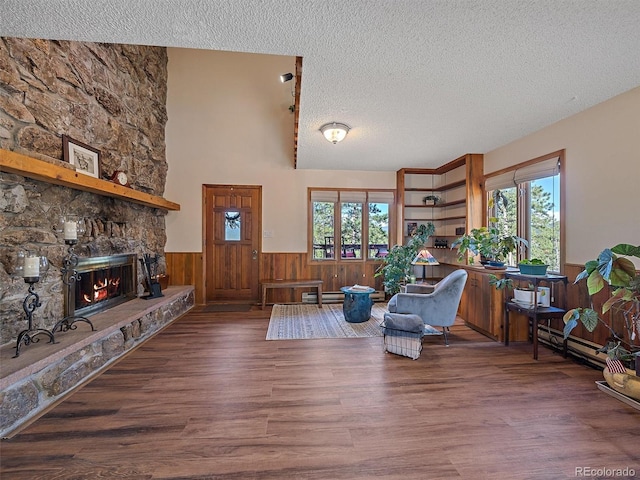 living room featuring hardwood / wood-style floors, a stone fireplace, plenty of natural light, and a textured ceiling