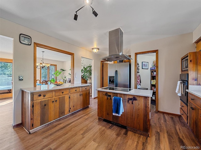 kitchen featuring hardwood / wood-style floors, black appliances, island range hood, and an inviting chandelier