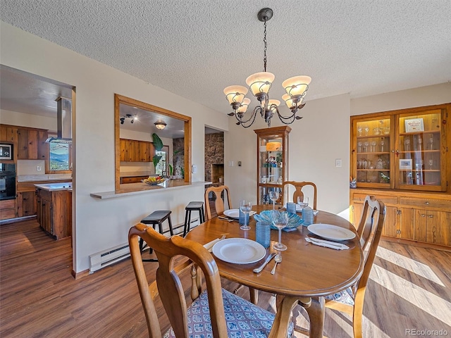 dining area with a fireplace, a chandelier, hardwood / wood-style floors, and a textured ceiling