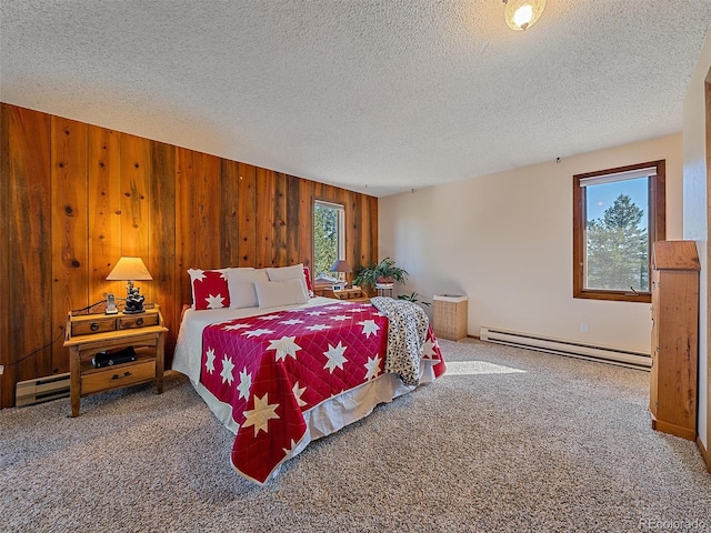 bedroom with baseboard heating, wood walls, a textured ceiling, and carpet floors