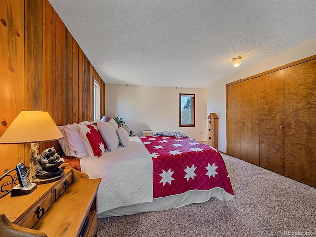 carpeted bedroom with wooden walls, a closet, and a textured ceiling