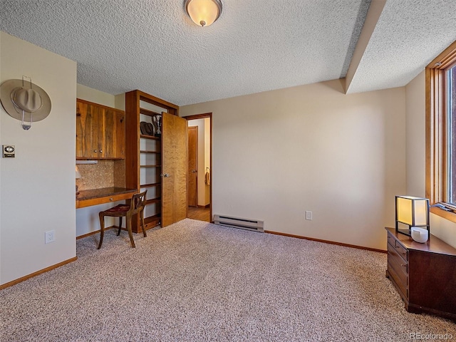 carpeted office space featuring a baseboard radiator, a textured ceiling, and built in desk