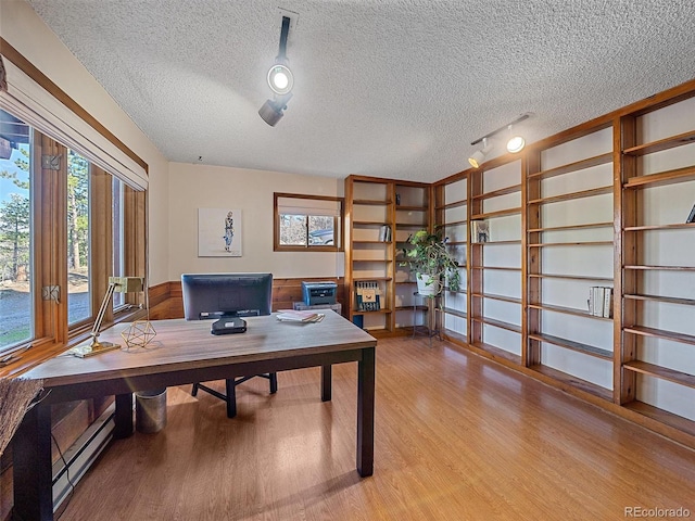 office area featuring a baseboard heating unit, hardwood / wood-style floors, plenty of natural light, and a textured ceiling