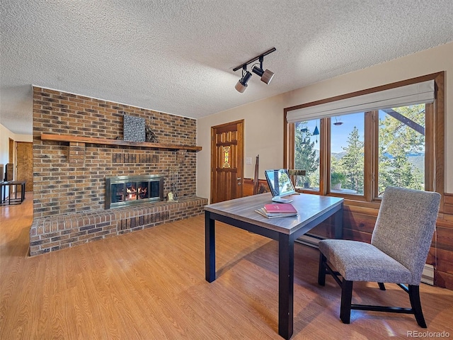 rec room with a textured ceiling, hardwood / wood-style flooring, and a brick fireplace