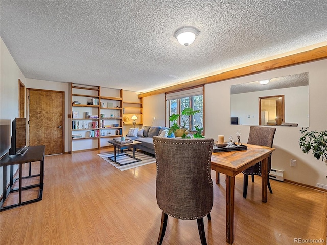 dining space featuring light hardwood / wood-style floors and a textured ceiling