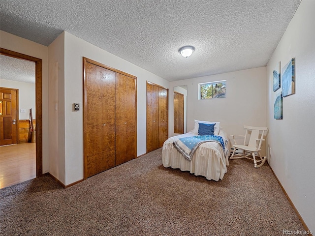 carpeted bedroom with a textured ceiling and two closets