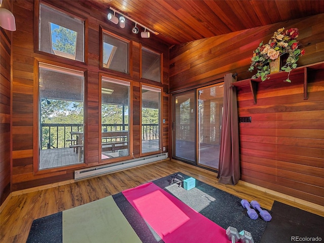 exercise area with wooden walls, hardwood / wood-style floors, wood ceiling, lofted ceiling, and baseboard heating