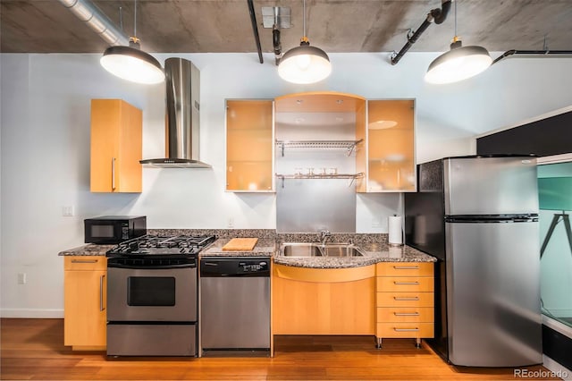 kitchen with sink, dark stone countertops, light hardwood / wood-style flooring, stainless steel appliances, and wall chimney exhaust hood