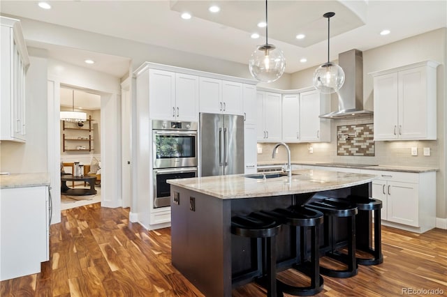4193 W 99th Ct, Westminster, CO 80031 - kitchen with appliances with stainless steel finishes, a sink, wall chimney exhaust hood, dark wood finished floors, and white cabinetry