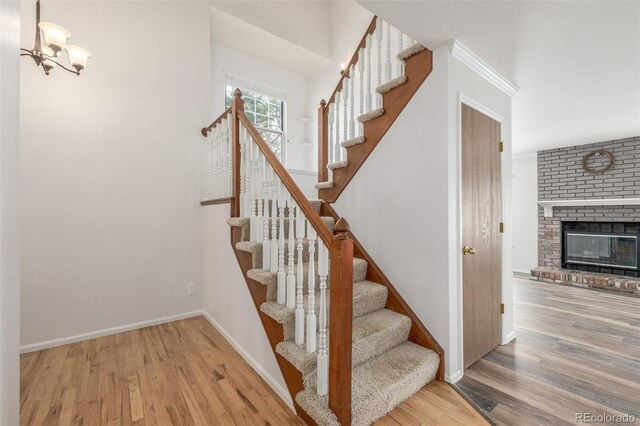 5316 S Jellison St, Littleton, CO 80123 - stairs with wood finished floors, baseboards, a brick fireplace, and a chandelier