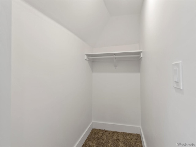 walk in closet with carpet flooring and vaulted ceiling