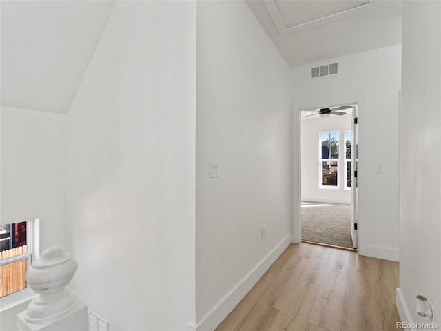 hall with lofted ceiling and light wood-type flooring