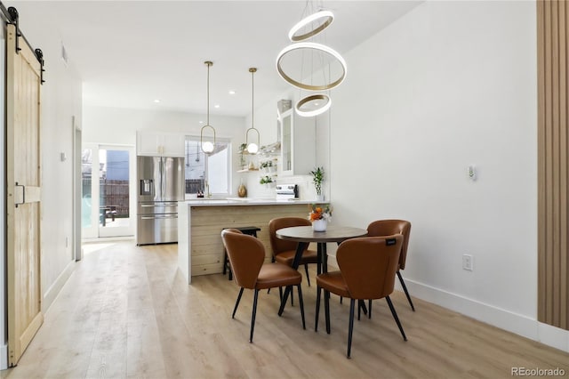 dining space with a barn door and light hardwood / wood-style floors