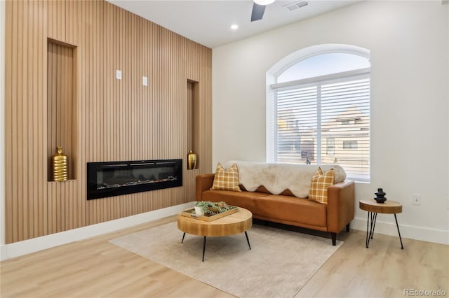 interior space featuring ceiling fan, a fireplace, light hardwood / wood-style floors, and wood walls