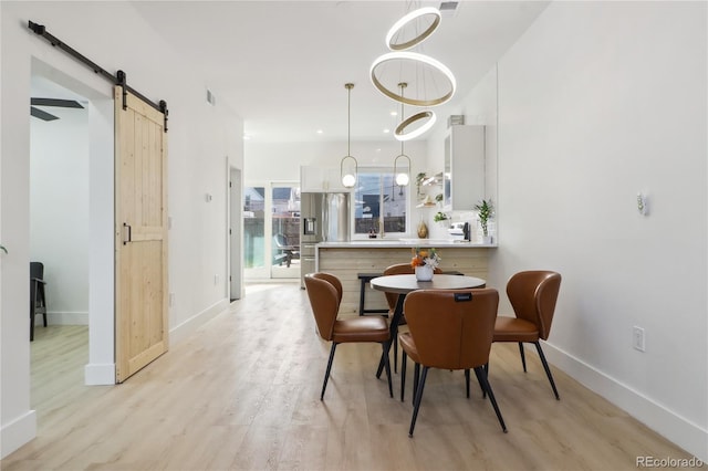 dining room featuring a barn door and light hardwood / wood-style floors