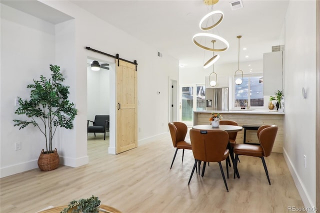 dining room featuring a barn door and light hardwood / wood-style flooring