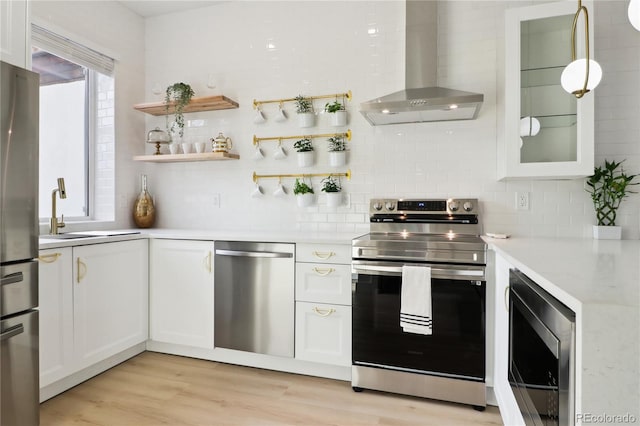 kitchen with white cabinetry, decorative light fixtures, stainless steel appliances, and wall chimney exhaust hood