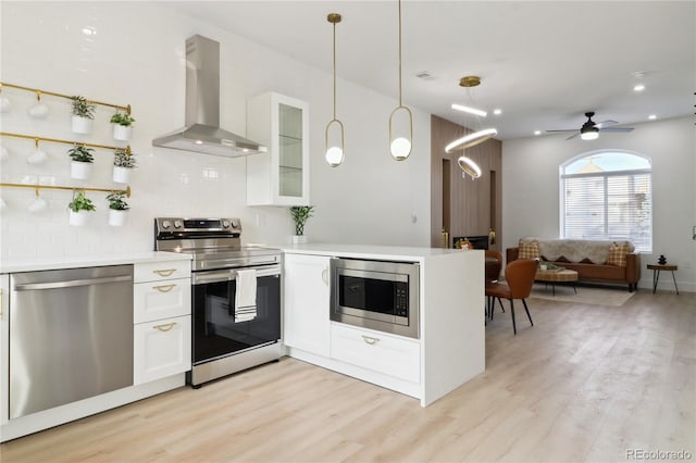 kitchen featuring white cabinetry, wall chimney range hood, tasteful backsplash, and stainless steel appliances