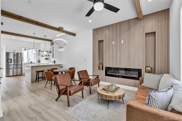 living room with ceiling fan, light hardwood / wood-style flooring, and beamed ceiling