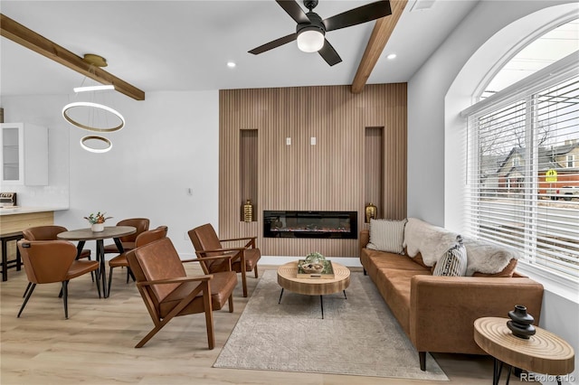 living room with ceiling fan, beam ceiling, and light hardwood / wood-style floors