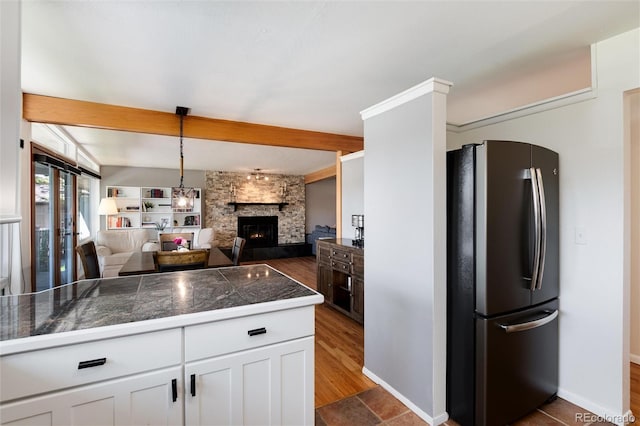 4545 S Lipan Ct, Englewood, CO 80110 - kitchen featuring freestanding refrigerator, tile counters, open floor plan, a stone fireplace, and white cabinets