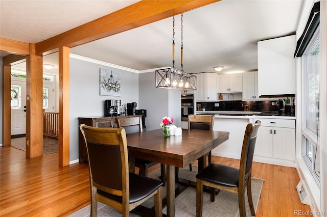 4545 S Lipan Ct, Englewood, CO 80110 - dining space featuring light wood-type flooring, healthy amount of natural light, a chandelier, and crown molding