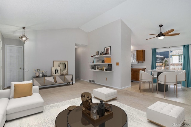 carpeted living room with ceiling fan with notable chandelier and vaulted ceiling