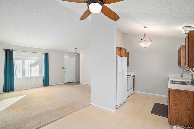 kitchen with pendant lighting, white appliances, sink, ceiling fan, and light colored carpet