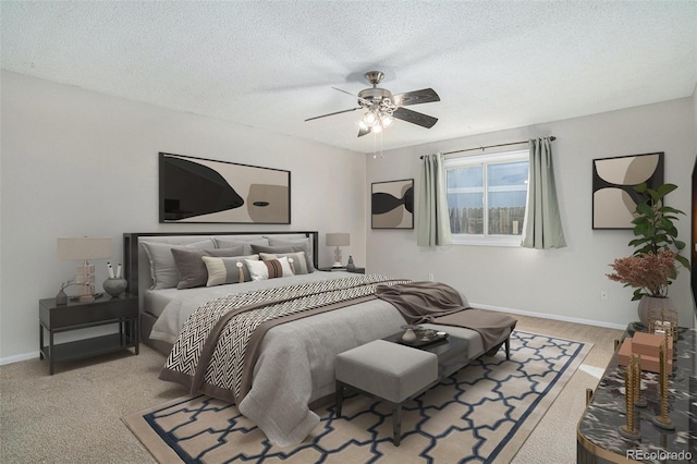 bedroom with ceiling fan, light colored carpet, and a textured ceiling