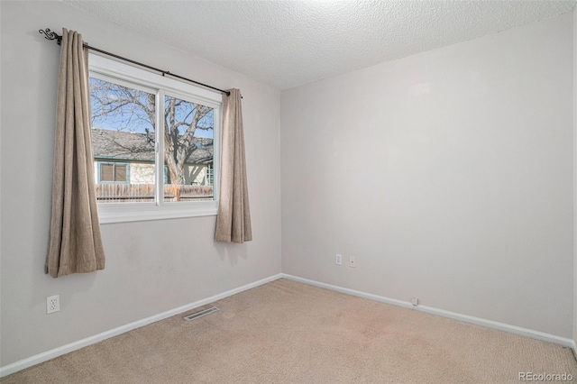 carpeted empty room featuring a textured ceiling