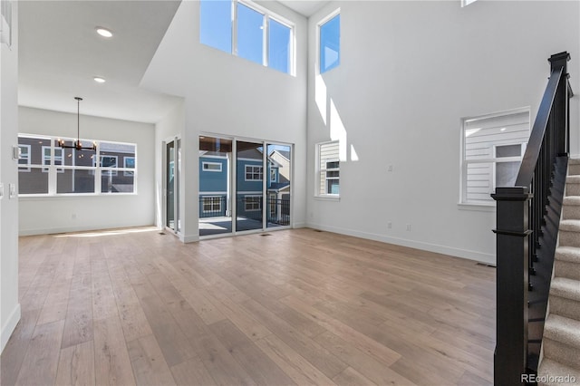 5626 W 142nd Ave, Broomfield, CO 80020 - unfurnished living room featuring stairs, a chandelier, wood finished floors, recessed lighting, and a towering ceiling