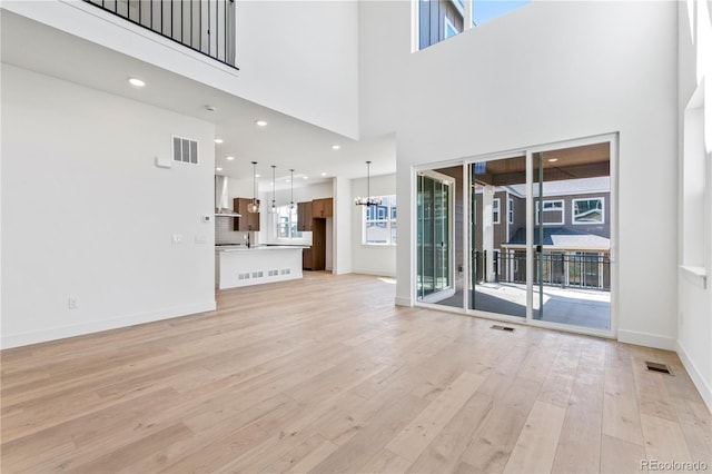 5626 W 142nd Ave, Broomfield, CO 80020 - unfurnished living room featuring light wood-style floors, a towering ceiling, a chandelier, and recessed lighting