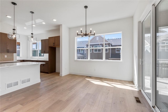 5626 W 142nd Ave, Broomfield, CO 80020 - kitchen with a chandelier, light wood-type flooring, light countertops, recessed lighting, and decorative backsplash