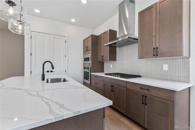 5626 W 142nd Ave, Broomfield, CO 80020 - kitchen with wall chimney exhaust hood, stainless steel appliances, backsplash, light wood finished floors, and decorative light fixtures