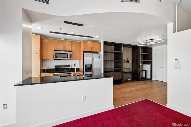 891 14th St Unit 2105, Denver, CO 80202 - kitchen with appliances with stainless steel finishes, a peninsula, dark countertops, wood finished floors, and recessed lighting