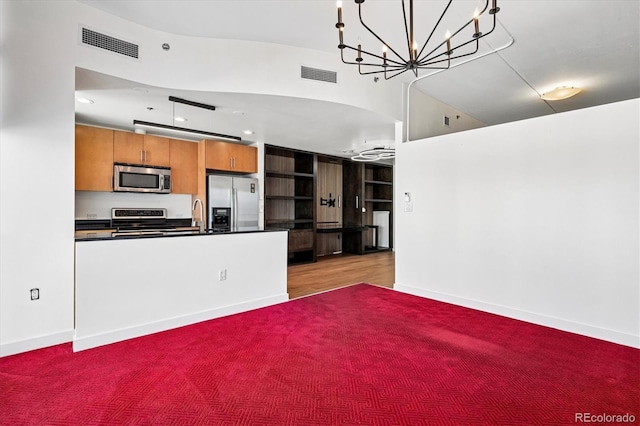 891 14th St Unit 2105, Denver, CO 80202 - kitchen with stainless steel appliances, dark countertops, brown cabinetry, a chandelier, and a peninsula