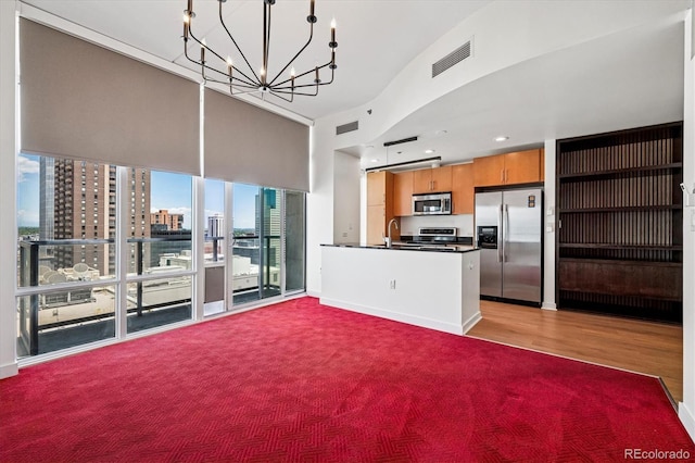 891 14th St Unit 2105, Denver, CO 80202 - kitchen featuring stainless steel appliances, a chandelier, dark countertops, brown cabinetry, and open floor plan