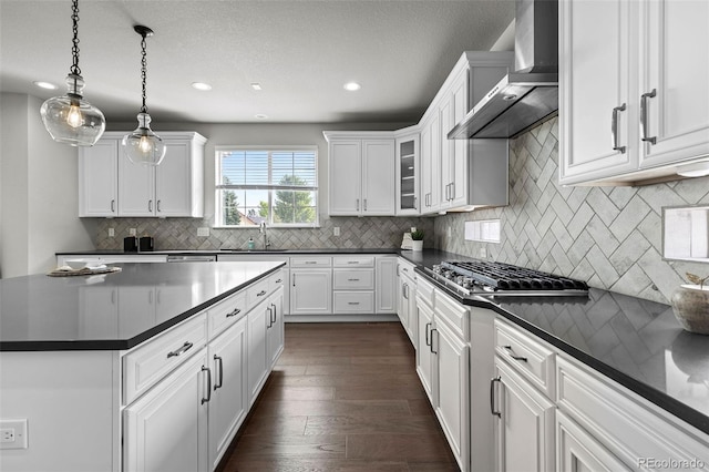 11522 Trona Ct, Parker, CO 80138 - kitchen featuring wall chimney exhaust hood, dark countertops, stainless steel gas stovetop, white cabinetry, and recessed lighting