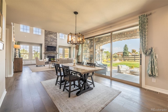 11522 Trona Ct, Parker, CO 80138 - dining space with a stone fireplace, a chandelier, dark wood-type flooring, and baseboards