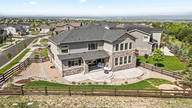 11522 Trona Ct, Parker, CO 80138 - back of house with stone siding, a patio, a fenced backyard, stucco siding, and a shingled roof