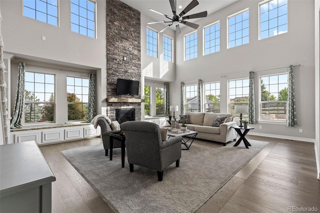 11522 Trona Ct, Parker, CO 80138 - living area featuring a high ceiling, a ceiling fan, a stone fireplace, wood finished floors, and baseboards