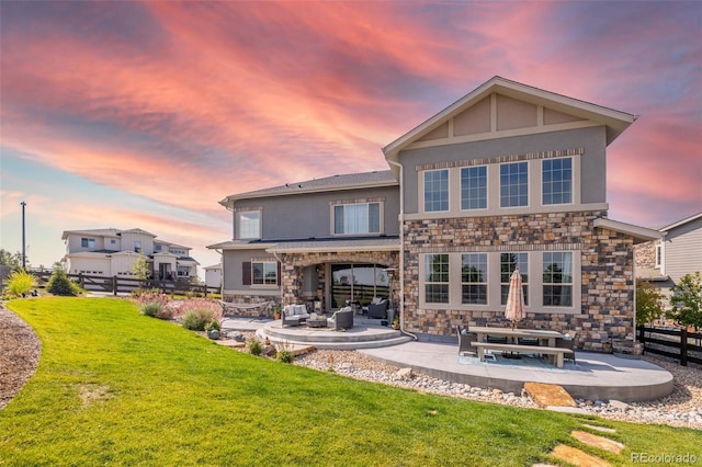 11522 Trona Ct, Parker, CO 80138 - back of house at dusk with a patio area, an outdoor living space, stone siding, and stucco siding