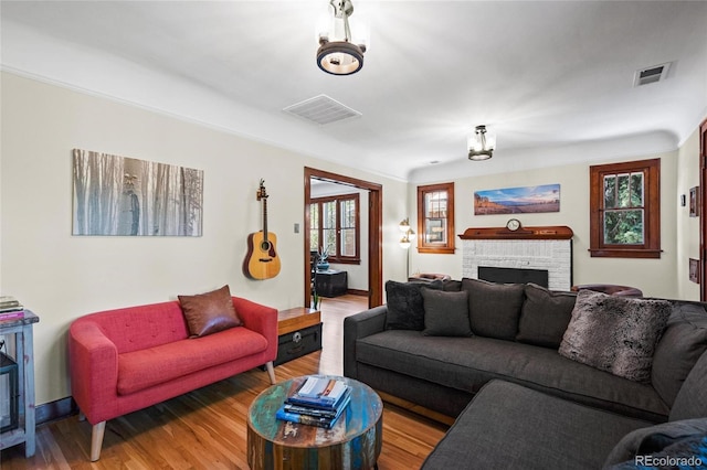 living area with wood finished floors, a brick fireplace, and baseboards