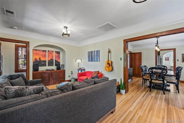 living area with light wood-type flooring, arched walkways, and baseboards