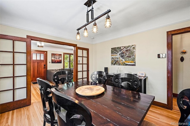 dining area with french doors, light wood-style flooring, and baseboards