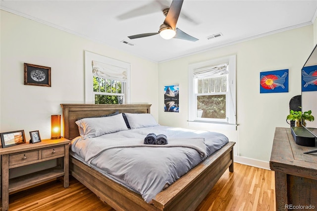 bedroom featuring ornamental molding, light wood-type flooring, baseboards, and a ceiling fan