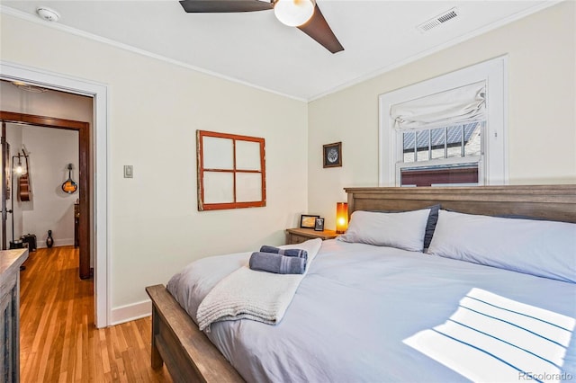 bedroom with crown molding, baseboards, light wood-style floors, and a ceiling fan