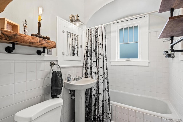 bathroom with toilet, tile walls, and tiled shower / bath